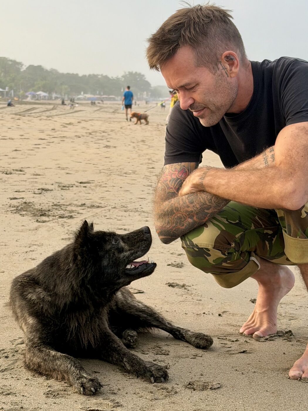 Stephan Mairesse face to face with a black dog on the beach
