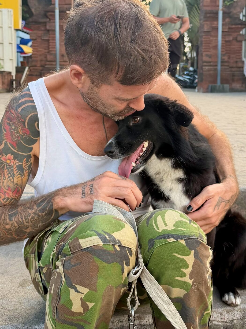 Stephan Mairesse face to face with a black and white dog at a temple