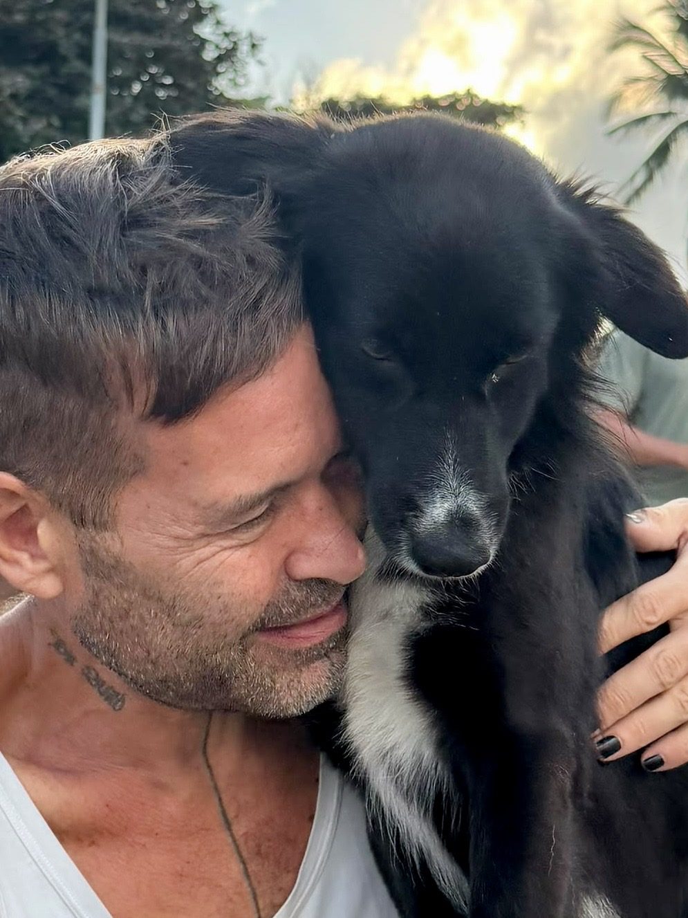 Stephan Mairesse with his head against Ruby's, the black and white dog resting calmly with her eyes half closed